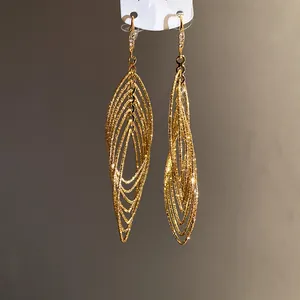 Detail shot of gold oval layered earrings with textured finish and zircon accents