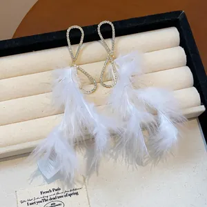 Dettaglio di eleganti orecchini con piume bianche e un cerchio con strass luccicanti