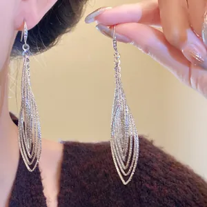 Close-up of elegant silver-colored oval pleated hollow dangle earrings with shimmering zircons