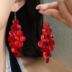 Close-up detail of vibrant red circular shell sequin fringe earrings for beach vacation style