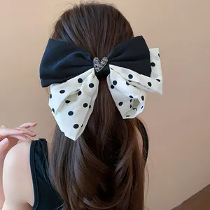 Elegant polka dot fabric bow hair clip with a sparkling crystal heart jewel detail