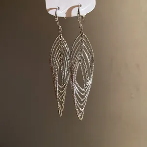Close-up detail of silver layered hollow teardrop dangle earrings with textured finish