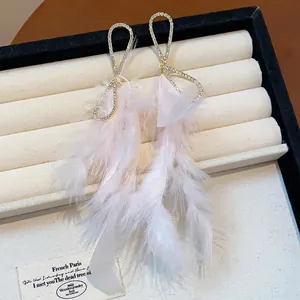 Dettaglio di eleganti orecchini a nappa in piume rosa chiaro con strass scintillanti.