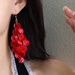 Close-up of elegant red shell tassel drop earrings on model for a vacation look