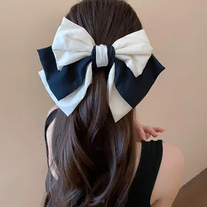 Elegant large black and white fabric bow hair clip shown on the back of wavy brown hair