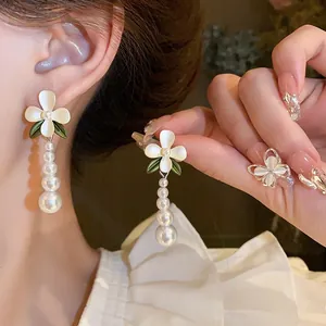 Detail shot of French vintage style white flower earrings with elegant pearl tassels and ring