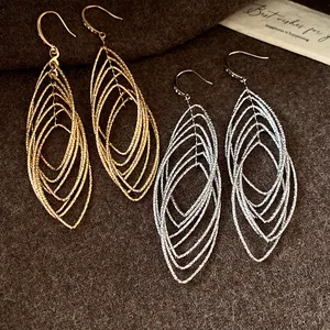 Close-up of vintage textured hollow oval drop earrings in gold and silver finishes