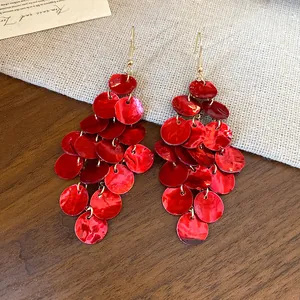 Detailed view of red tiered shell disc tassel earrings for a beach vacation look.