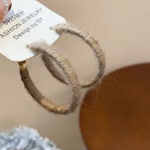 Detailed view of autumn-winter brown yarn-wrapped hoop earrings with soft woven texture