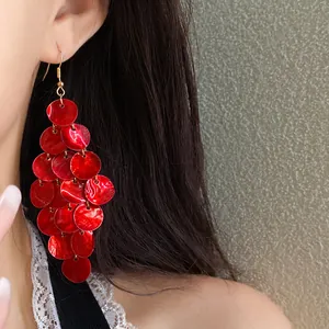 Close-up detail of vibrant red shell disc tassel earrings worn by an Asian model