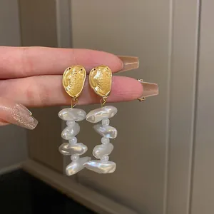Close-up of vintage French earrings with baroque pearls and gold hammered texture