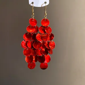 Detailed close-up of red layered round shell tassel earrings with vibrant luster.