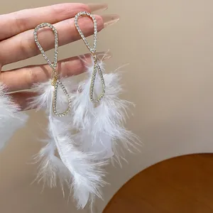 Eleganti orecchini pendenti dorati con strass brillanti e morbide piume bianche