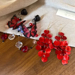 Detailed macro shot of red butterfly beads and shell disk tassel earrings for summer vacation