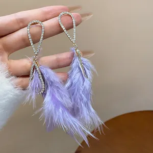 Primo piano dettagliato di eleganti orecchini a nappa con piume viola e strass luccicanti