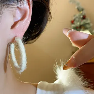 Detailed view of white fabric woven circular hoop earring with fuzzy texture on ear