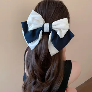 Detailed view of a large black and white fabric bow hair clip on long wavy hair.