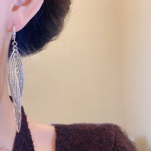 Detail shot of elegant silver pleated hollow oval drop earrings with shimmering zircon inlay