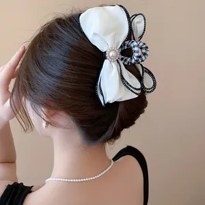 Elegant white fabric bow hair claw clip with pearl center on model's hair