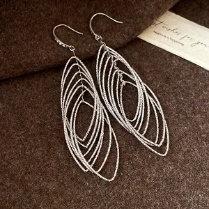 Close-up of vintage silver elliptical pleated hollow dangle earrings on felt background