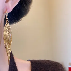 Close-up view of vintage gold plated oval cutout earrings with zircon accents on model
