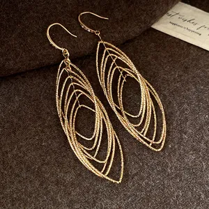 Macro detail view of gold-toned layered elliptical hollow earrings with textured surface