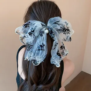 Detailed view of a stylish black and white lace bow hair clip with pearl ornament