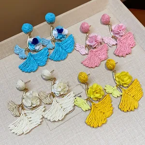 Detail view of woven raffia ginkgo leaf earrings with fabric flowers in four colors