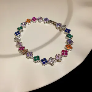 Close-up of a sparkling silver bracelet with colorful zircon four-leaf clover charms.