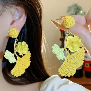 Detailed view of handmade yellow raffia ginkgo leaf earrings with delicate floral accents.
