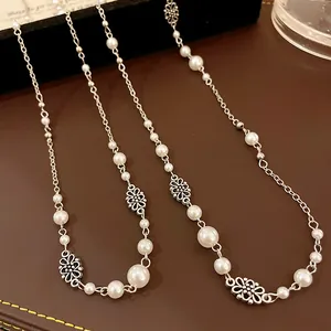 Close-up detail of a French retro necklace with white faux pearls and silver flowers.