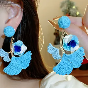 Close-up showing the intricate raffia weave and fabric flower detail of the earrings