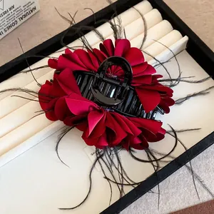 Elegant red fabric flower hair claw clip with black feather accents for women
