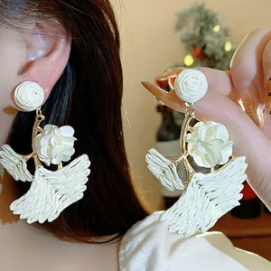 Close-up view of elegant white raffia ginkgo leaf earrings with gold accents.