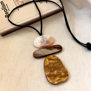 Detailed view of geometric resin pendants on a retro black leather cord sweater chain