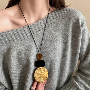 Detail of vintage geometric resin necklace with marbled pendant on a grey sweater