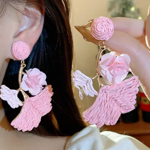 Close-up of pink raffia earrings with floral design and ginkgo leaf shape