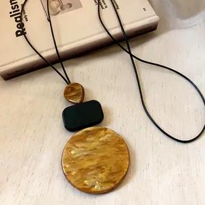 Close-up of geometric resin pendants featuring an amber marble texture on black cord