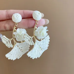 Detailed macro of white raffia woven ginkgo leaf earrings with fabric roses decoration