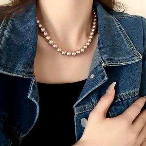 Detail of champagne pearl necklace worn with a denim jacket for a chic retro look