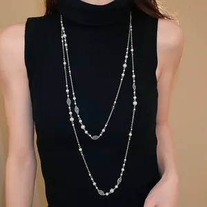 Macro detail of long French retro style necklace featuring artificial pearls and silver flowers