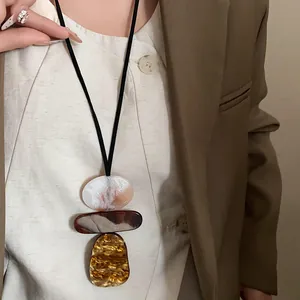 Close-up detail of a vintage geometric resin pendant necklace on a stylish sweater.
