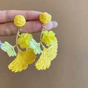 Detail showing the intricate woven texture of yellow raffia ginkgo leaf earrings
