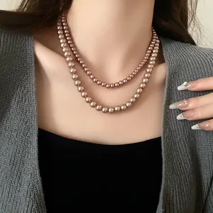 Detail view of an elegant double-layer pearl necklace worn by a model in grey outfit