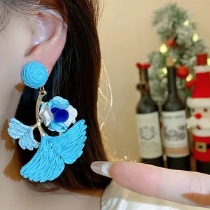 Macro shot of a light blue raffia ginkgo leaf earring featuring fabric flower detail