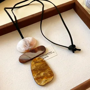 Detail of geometric resin pendants with marble swirl patterns on a black cord