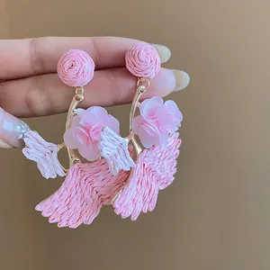 Detailed macro view of pink raffia ginkgo leaf earrings with soft fabric flower accents