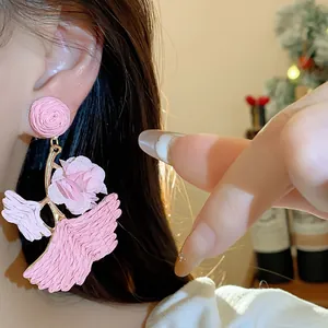 Close-up detail of stylish pink raffia ginkgo leaf earrings with silver needle on ear