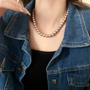 Elegant rose gold pearl necklace worn over a classic denim jacket and black top.