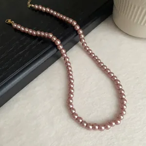 Close-up of dusty rose pearl necklace with golden clasp and extender chain